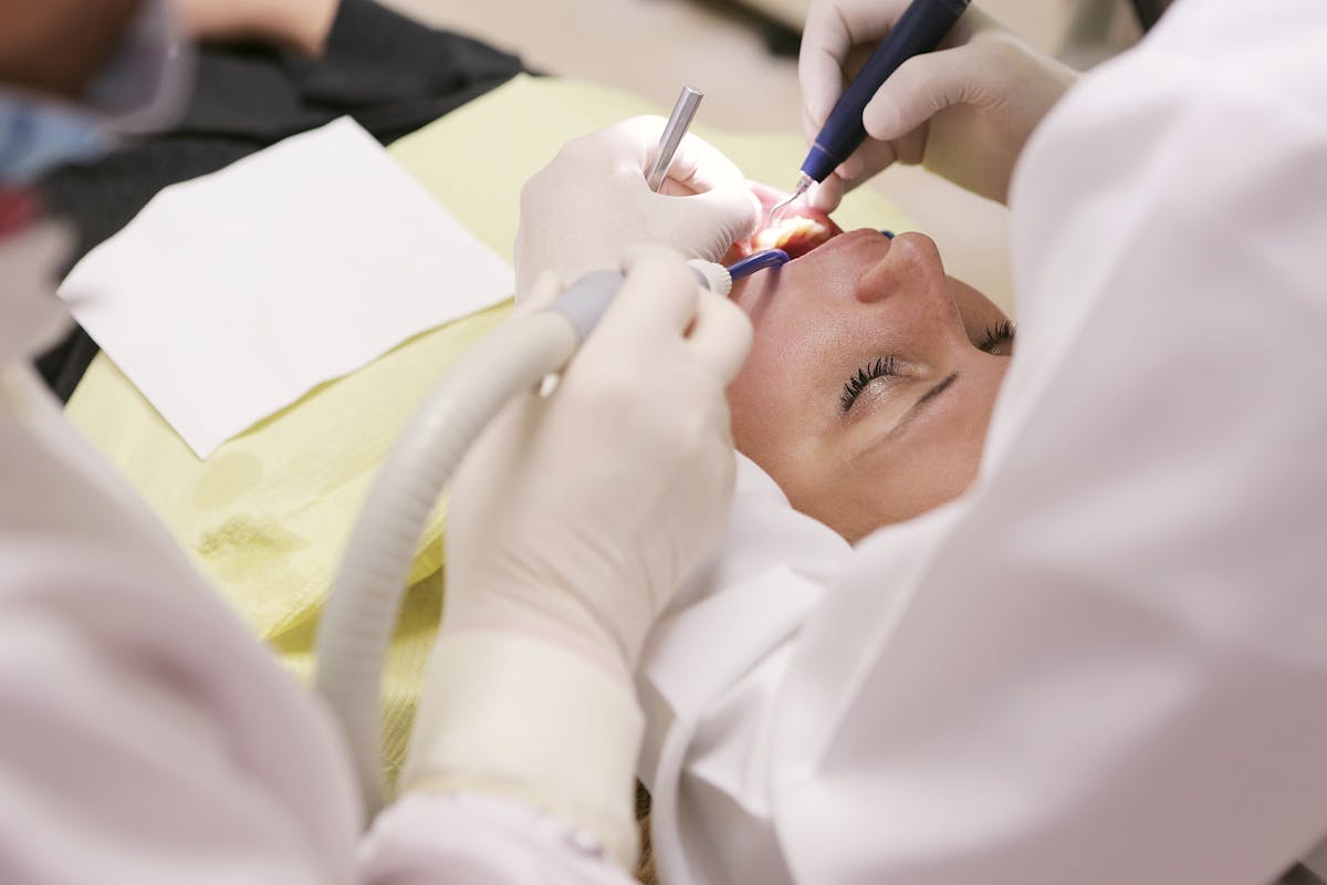 People Wearing White Shirt Working on Womans Teeth